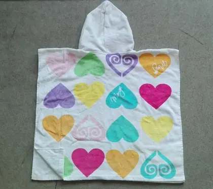 White hooded children's poncho towel printed with colorful pink, purple, teal, yellow, and orange hearts on a gray background