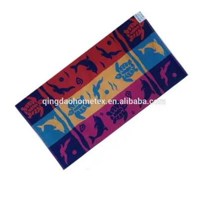Colorful beach towel with dolphin, turtle, and bird patterns in red, blue, orange, and purple, laid diagonally on white