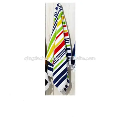 Colorful striped beach towels with fringed edges hanging on a white wooden wall