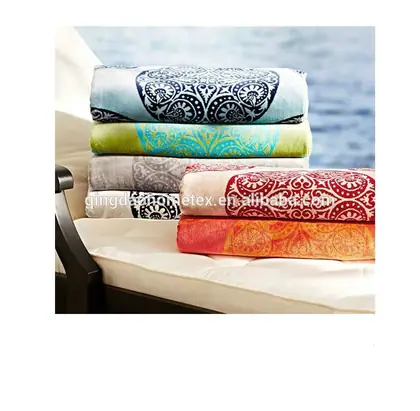 Stack of colorful patterned folded towels on an outdoor lounge chair near the sea