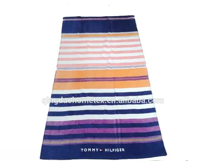 Striped beach towel in navy, pink, orange and purple with Tommy Hilfiger branding on a white background