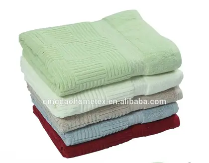 Stack of folded towels in green, white, beige, blue, and red on a plain background, with BSCI and Confidence in Textiles logos below
