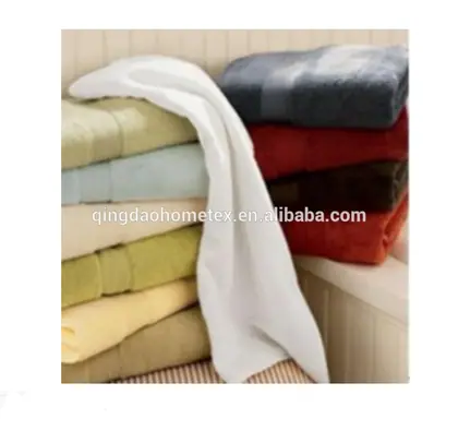 Stacks of folded terry towels in assorted colors, including white, beige, blue, red, and brown