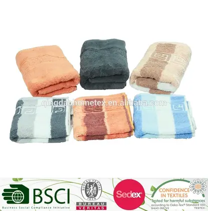 Six folded towels in orange, dark grey, beige, striped and blue patterns arranged in two rows on a white background
