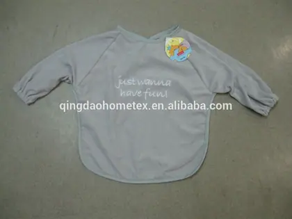 Gray long-sleeve baby smock bib with printed text and cartoon tag, laid flat