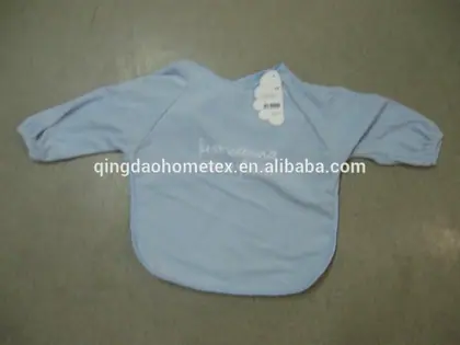 Light blue long-sleeve baby bib with embroidered text and a tag, laid flat on a gray surface