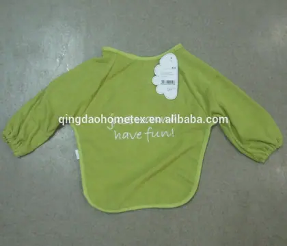 Green long-sleeve baby bib with embroidered text and a paper tag, laid flat on a gray floor