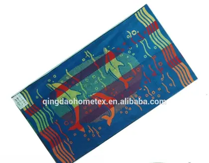 Colorful blue beach towel with dolphin and fish patterns laid at an angle, with BSCI and Oeko-Tex certification logos below