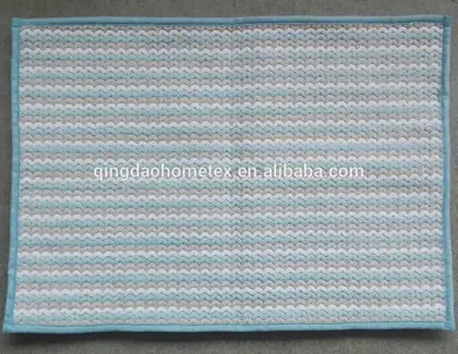 Woven mat with blue, grey and white zigzag stripes and light blue border on grey surface