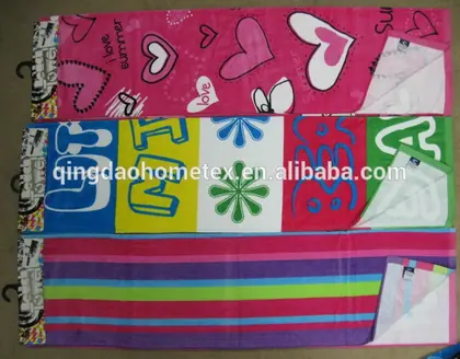 Three colorful beach towels with heart, lettering, and stripe patterns hanging on a wall