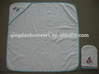 White baby hooded towel with embroidered fish and boat details and matching wash mitt on grey background