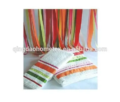 Folded white towels with colorful stripes and ribbon borders, colorful ribbons hanging in the background