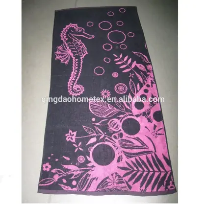 Dark grey beach towel with pink seahorse and floral print laid on a floor