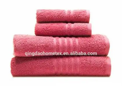 Stack of four rolled pink cotton towels of decreasing size on a white background