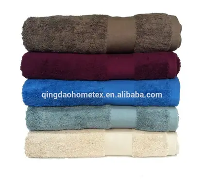 Stack of five folded towels in brown, burgundy, blue, light blue, and beige on a white background
