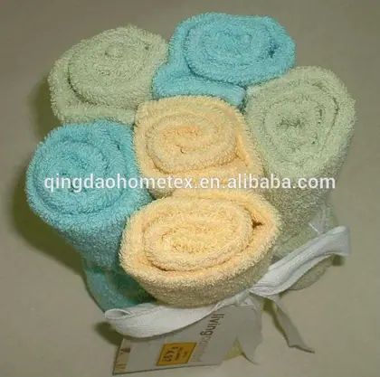 Rolled towels in pastel blue, green and yellow arranged in a flower shape and tied with a white ribbon