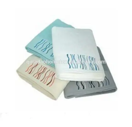 Four folded towels in white, teal, cream, and grey with wavy embroidered stripes