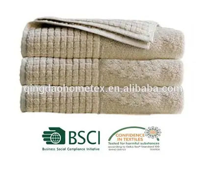 Stack of folded beige towels with waffle weave bands on white background