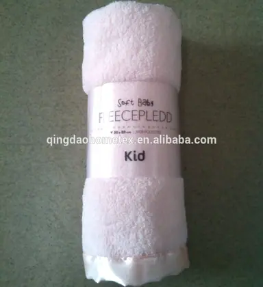 Rolled pale pink fleece baby blanket with satin trim and printed packaging band reading Kid