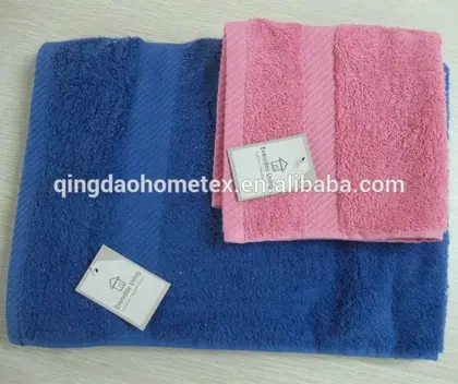 Folded blue and pink terry towels with paper tags on a white surface