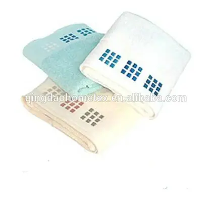Three folded towels in white, light blue, and cream with blue and red square-pattern borders on a white background