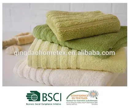 Stack of folded green and cream terry towels with loofahs in the background