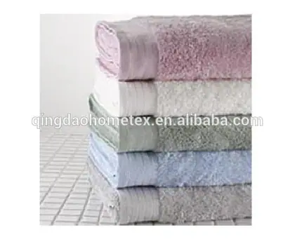 Stack of folded pastel terry towels in pink, white, green, blue and grey on a tiled surface