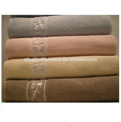 Stack of four folded terry towels in grey, pink, cream, and brown with embroidered floral bands