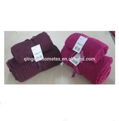 Rolled burgundy and magenta coral fleece blankets with retail tags and pink ribbons on a table