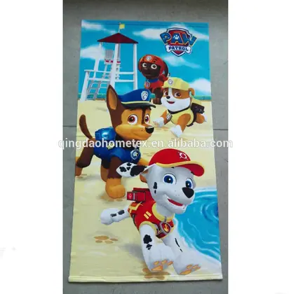 Beach towel printed with Paw Patrol cartoon characters laid flat on a tiled floor
