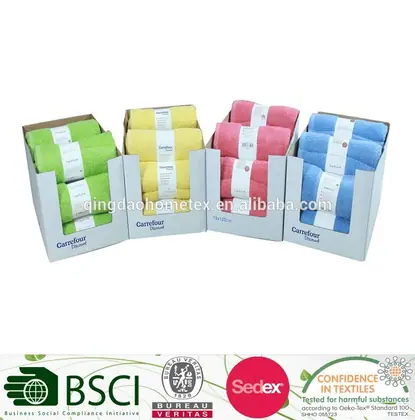 Four cardboard display boxes of rolled towels in green, yellow, pink, and blue, with certification logos overlaid below