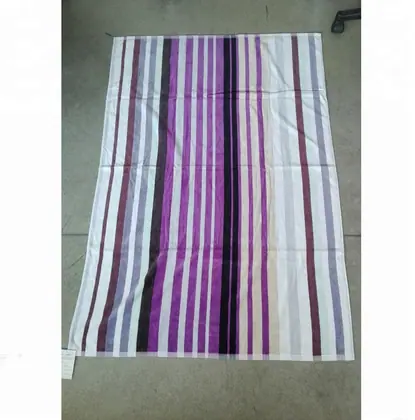 Striped towel or fabric with purple, magenta, black and white vertical stripes laid flat on a gray floor