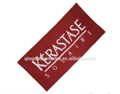 Red beach towel with white Kerastase Solaire branding on white background, with BSCI and Oeko-Tex logos below