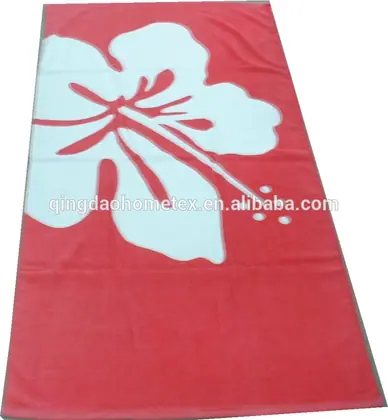 Red beach towel with a large white hibiscus flower print, laid flat
