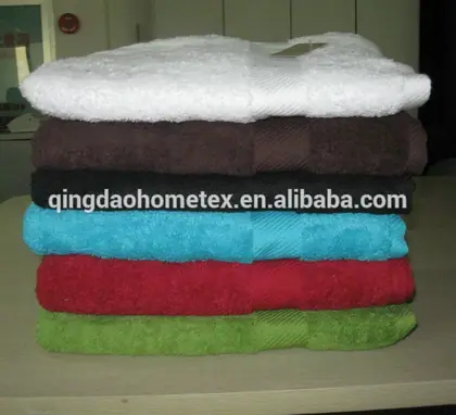 Stack of folded terry towels in white, brown, black, turquoise, red, and green on a table