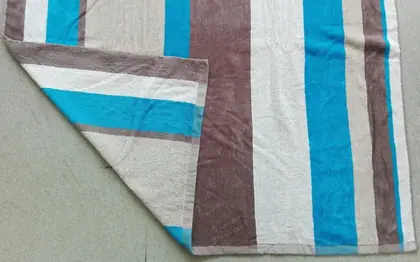 A striped towel with vertical bands of teal, brown, and beige, folded to show its texture.