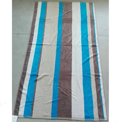 Striped beige, brown, and blue woven mat or rug laid flat on a grey tiled floor.