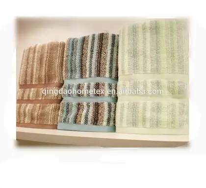 Stacked striped folded towels in brown, multicolor, and pale green on a white shelf