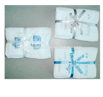 Three folded white bath towels tied with silver and blue ribbons, embroidered with bath and H2O text