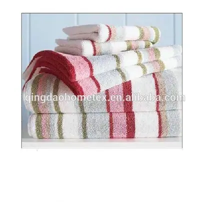 Stack of folded striped towels in red, pink, green and white on a white shelf