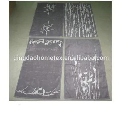 Four gray jacquard towels with white tree and bird designs laid flat on a floor