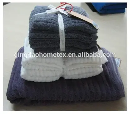 Stack of folded gray, white, and dark purple towels tied with ribbons and a paper hang tag on a table