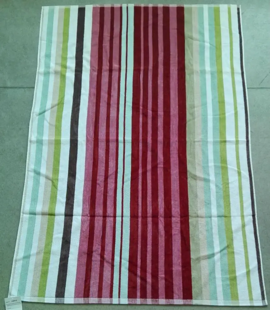 Multicolored striped towel in burgundy, pink, green, and white lying flat on a grey floor