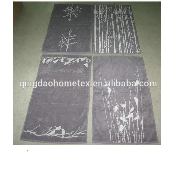 Four gray jacquard towels with white tree and bird designs laid flat on a floor