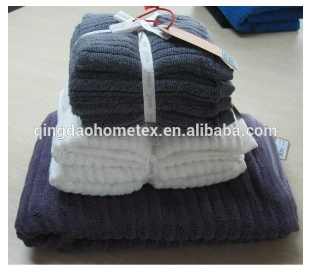 Stack of folded gray, white, and dark purple towels tied with ribbons and a paper hang tag on a table