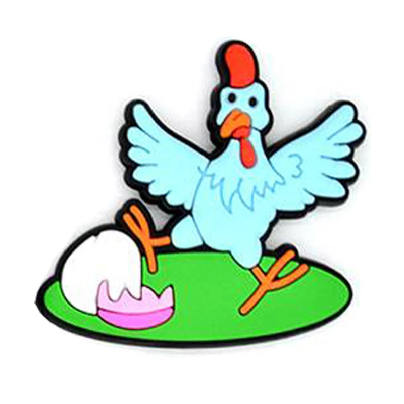 Soft PVC magnet of a pale blue rooster with spread wings standing on a green base beside a white egg