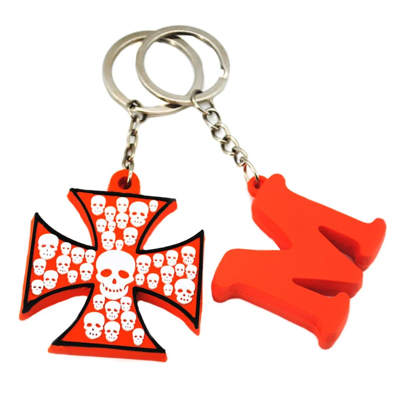 Two moulded rubber key chains one a red cross with white skull pattern and one a pair of red chilli peppers