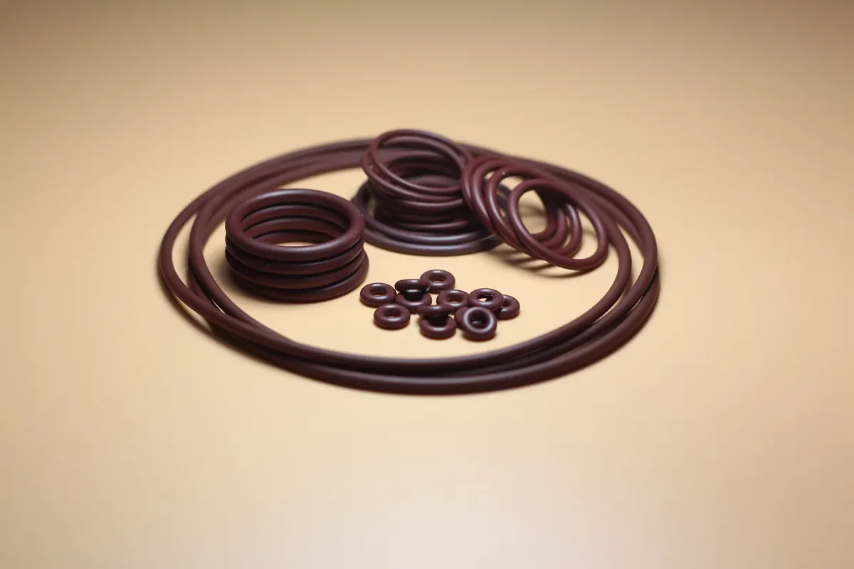 Dark red EPDM sealing rings of varying diameters arranged on a tan surface