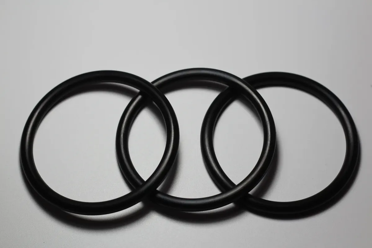 Four black nitrile O-rings of graduated diameter arranged on a light surface