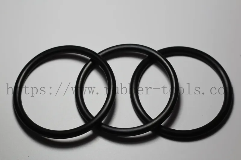 Four black nitrile O-rings of graduated diameter on a light grey surface